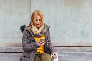 Porträt einer blonden Frau, die ihr Mobiltelefon auf der Straße benutzt - ADSF03160