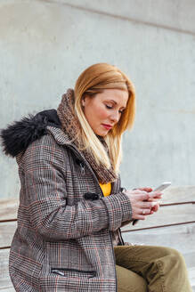 Porträt einer blonden Frau, die ihr Mobiltelefon auf der Straße benutzt - ADSF03161