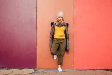 Blonde girl leaning on a colorful wall - ADSF03167