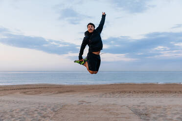 Runner jumping on the beach at sunrise. - ADSF03204