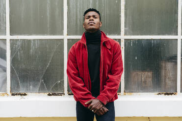 Seriöser junger schwarzer Mann mit rotem Pullover im Freien - ADSF03213