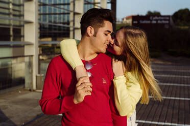 Attractive young couple standing in city and kissing tenderly - ADSF03251