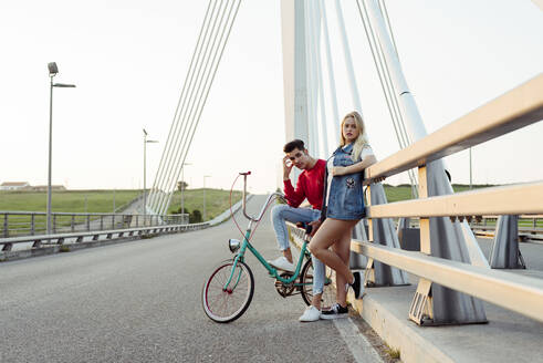 Junges Paar steht auf einer Brücke mit einem alten Fahrrad - ADSF03252