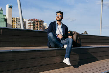 Stylish man relaxing with music on seafront - ADSF03267