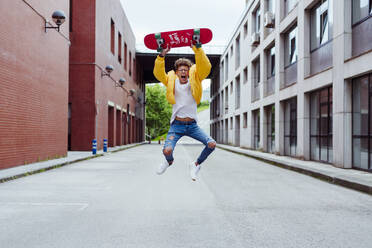 Glücklicher und aufgeregter Teenager, der mit dem Skateboard springt - ADSF03382