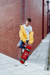 Teenager with skateboard on corner - ADSF03385