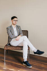 Thoughtful stylish young man on chair - ADSF03430