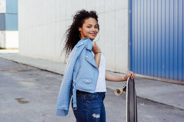 Teenager with skateboard on street - ADSF03473