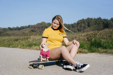 Mädchen mit Hund auf Longboard in der Natur - ADSF03519