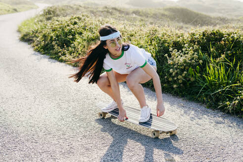 Trendy Teenager-Mädchen reitet Brett auf der Straße - ADSF03524