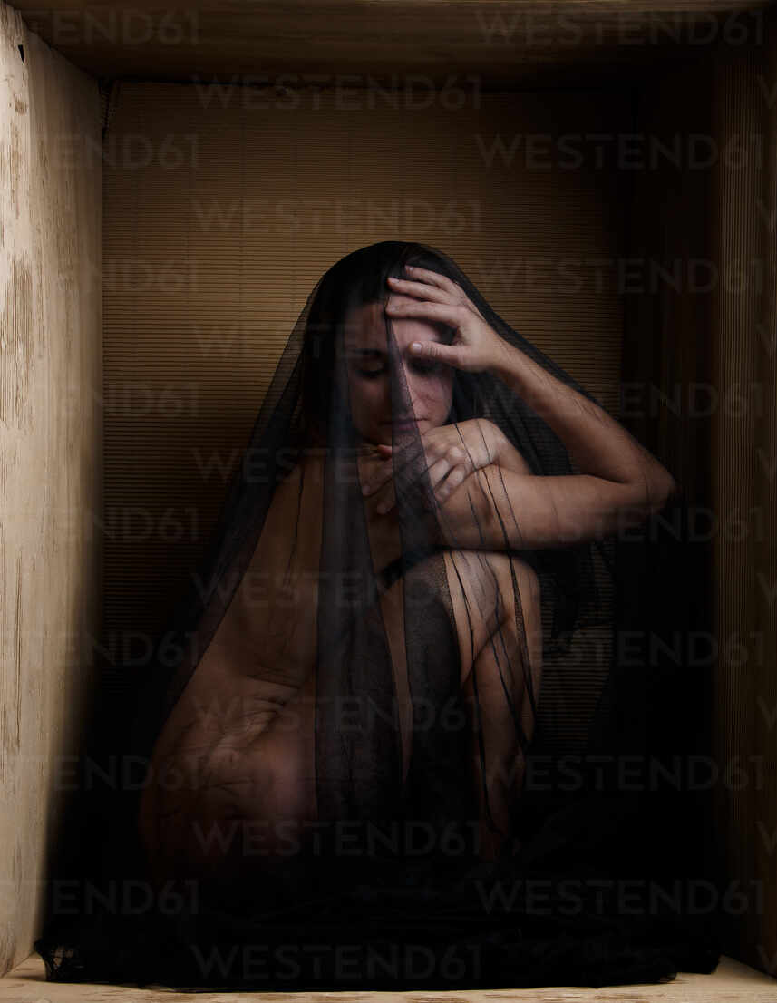 Back view of sensual naked woman sitting in limits of carton box looking up  stock photo