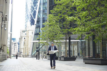 Unternehmerin liest Zeitung beim Spaziergang in der Stadt - PMF01245