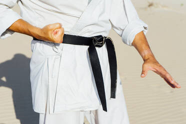 Nahaufnahme eines reifen Mannes, der am Strand stehend Karate übt - CJMF00325