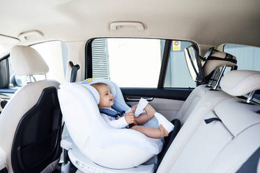 Baby im Kindersitz sitzend und in den Spiegel schauend in einem Auto - JCMF01039
