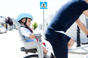 Father with son sitting in safety seat of bicycle - JCMF01044