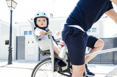 Father with son sitting in safety seat of bicycle - JCMF01045