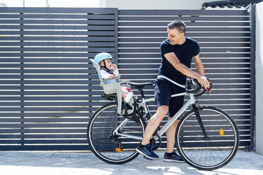 Vater mit Sohn auf dem Sicherheitssitz eines Fahrrads - JCMF01047