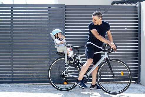 Vater mit Sohn auf dem Sicherheitssitz eines Fahrrads - JCMF01047