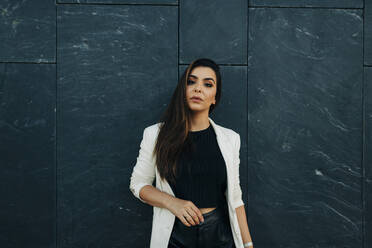 Portrait of young woman in front of black wall - DCRF00516