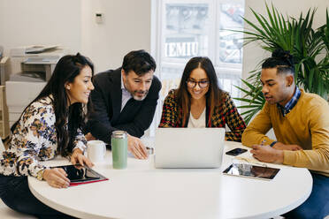 Multiracial office working men and women sitting at the table and using laptop. - ADSF03635