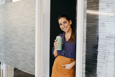 Smiling woman with cup in office - ADSF03649