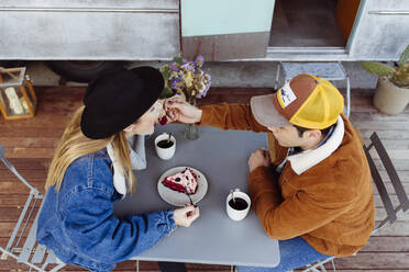 Junger Mann und Frau genießen leckeren Kuchen, während sie an einem Tisch in der Nähe eines schmuddeligen Lieferwagens sitzen - ADSF03724