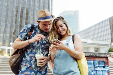 Couple browsing smartphone on street - ADSF03760