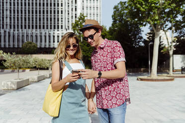 Couple browsing smartphone on street - ADSF03763