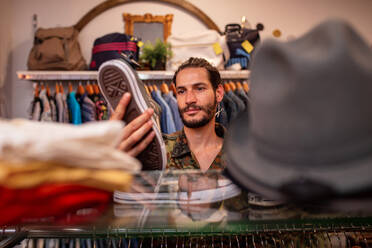 Cheerful man choosing clothing and accessories in shop - ADSF03802