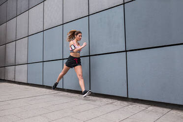 Athletic woman jogging on street - ADSF03874