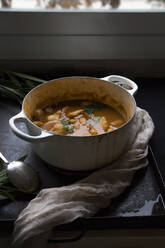 Leckere gekochte Suppe mit Kartoffeln in weißem Topf auf einem Tisch serviert. - ADSF03925