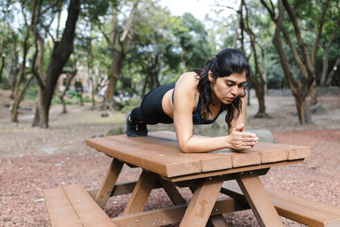 Young woman during workout outdoors, plank on table - JMPF00221