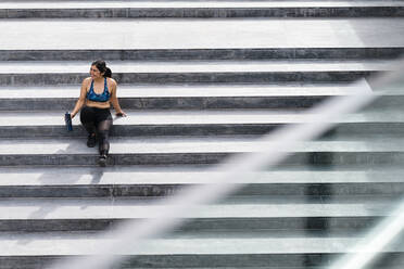 Young athletic woman sitting on stairs during break - JMPF00222