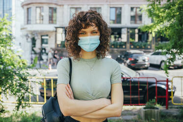 Brunette curly woman wearing protective mask in city - OYF00145