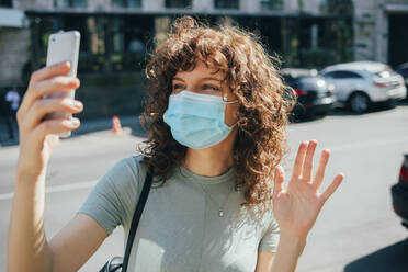 Woman wearing protective mask and using smartphone in city - OYF00149