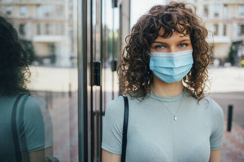 Brunette curly woman wearing protective mask in city - OYF00155