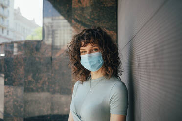 Brunette curly woman wearing protective mask in city - OYF00156