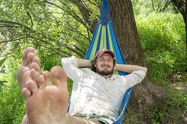 Mann entspannt auf Hängematte im Wald - VPIF02615