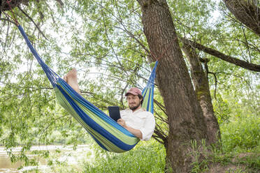 Man relaxing on hammock in the forest - VPIF02629