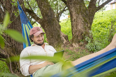 Mann entspannt auf Hängematte im Wald - VPIF02630