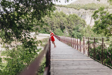 Frau in rotem Kleid auf der Sankt-Paul-Brücke in Cuenca, Spanien - MRRF00124