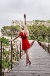 Ballerina wearing red dress on Saint Paul Bridge in Cuenca, Spain - MRRF00127