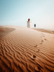 Back view of tourist standing at beacon in sandy dunes - ADSF04025