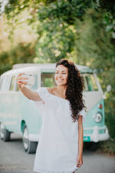 Fröhliche Frau macht Selfie in der Nähe eines Lieferwagens - ADSF04107