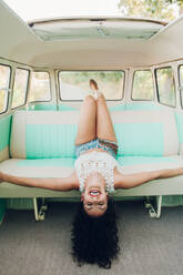 Schöne junge Brünette lachend auf dem Rücksitz eines Retro-Vans während eines Ausflugs in die Natur liegend - ADSF04108
