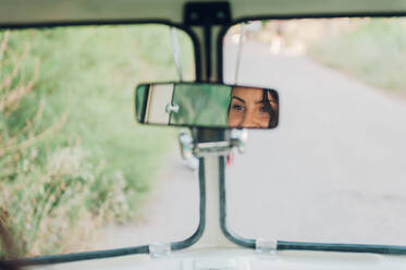 Reflexion einer jungen Frau im Rückspiegel eines Retro-Autos während eines Ausflugs in die Natur - ADSF04113