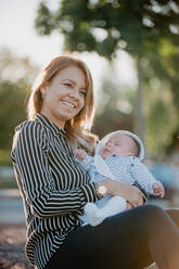 Junge Mutter, die ihr Baby mit Down-Syndrom umarmt - ADSF04126