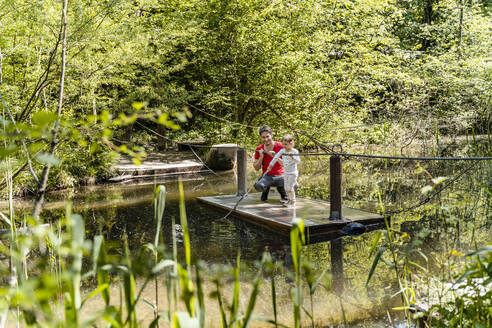 Vater und Tochter auf einem Holzfloß über einem See im Wald - DIGF12761