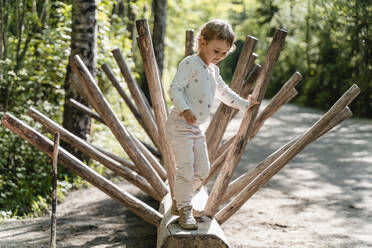 Niedliches Mädchen steht auf Holz im Wald - DIGF12763