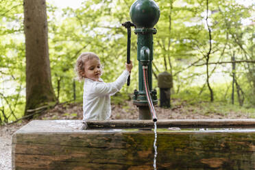 Nettes Mädchen spielt mit Brunnen gegen Bäume im Wald - DIGF12791